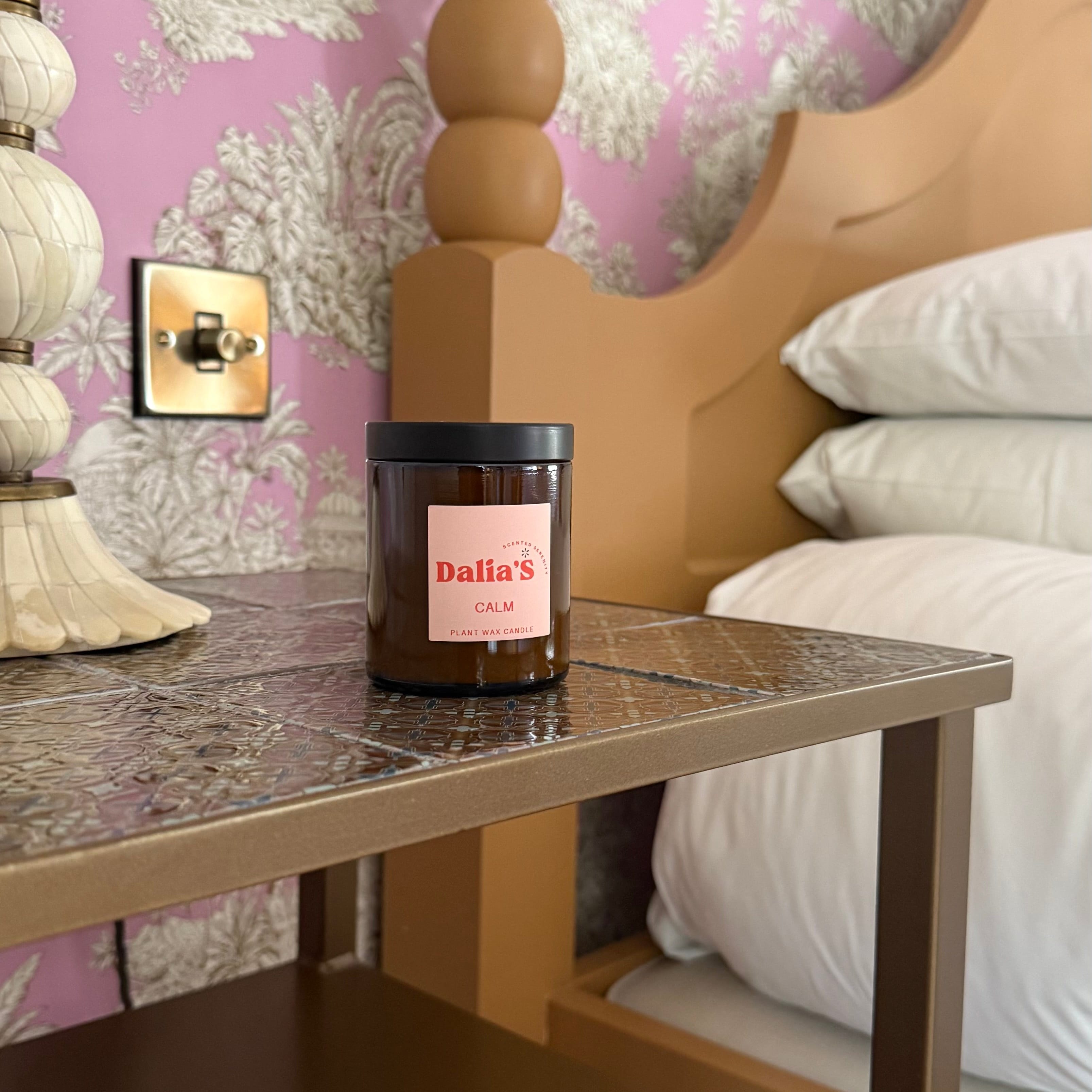 Dalias candle on a nightstand with floral wallpaper in the background