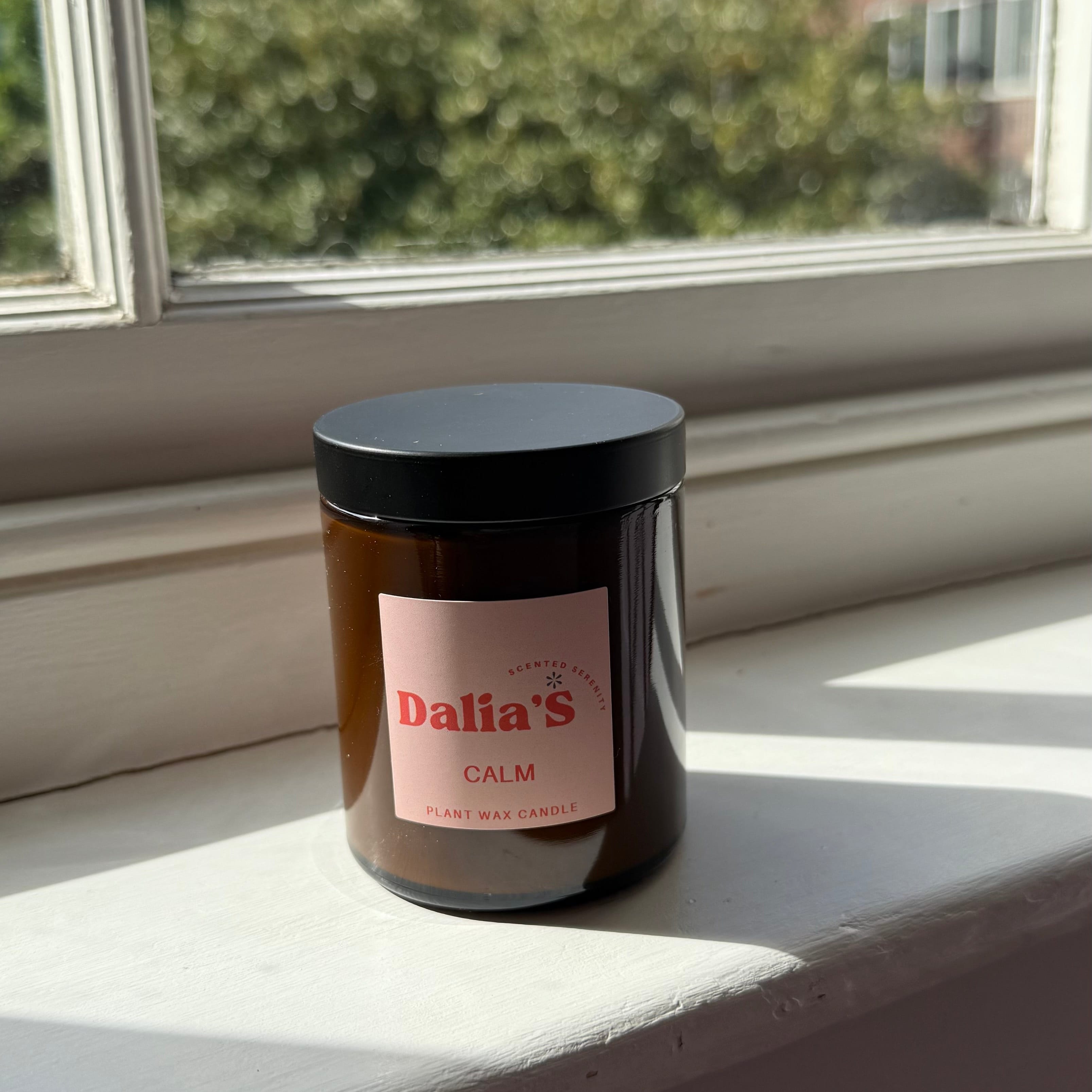 Jar with a label on a windowsill with a view of buildings and trees outside.