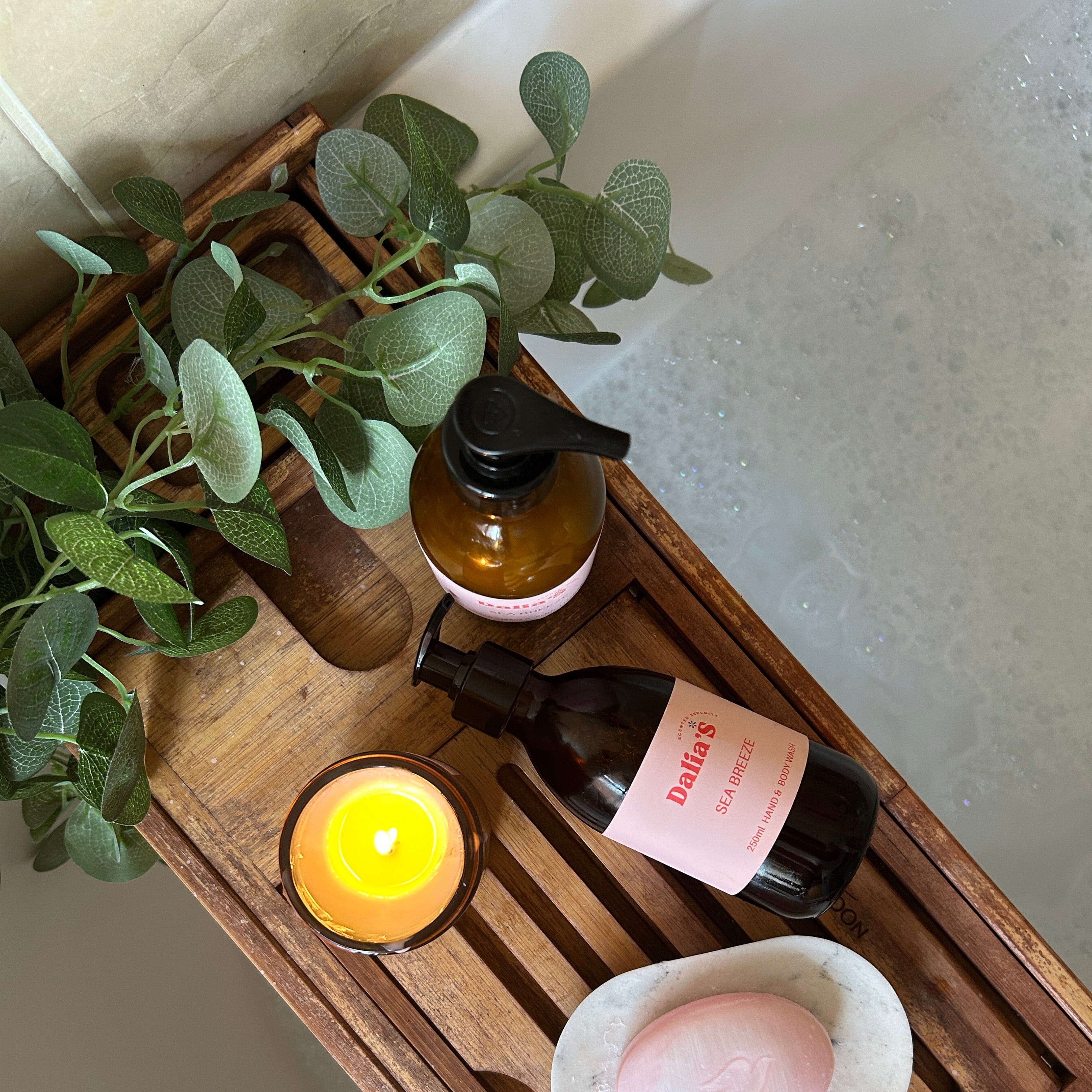 Wooden tray with bottles, a candle, and a soap on a neutral background