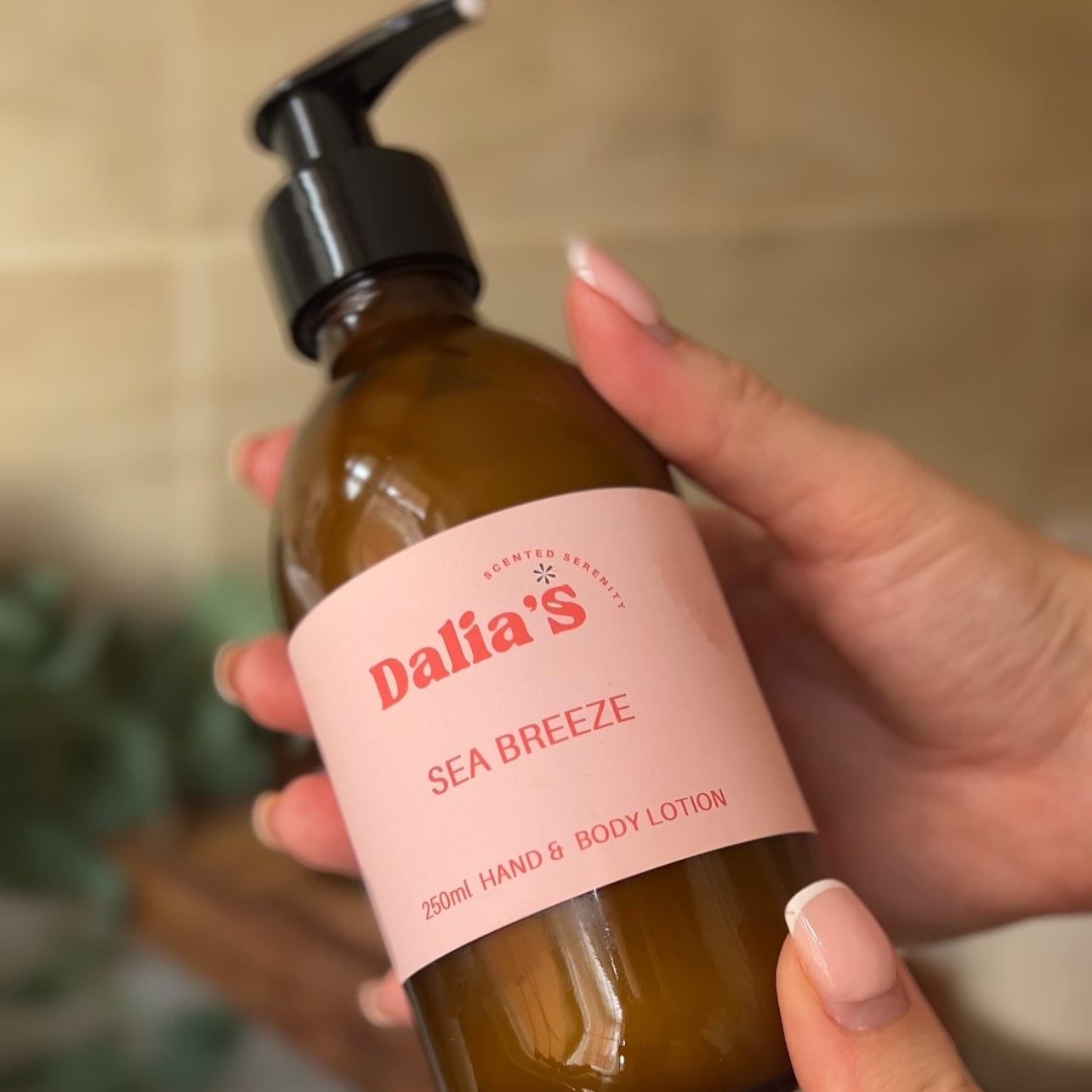 Hand holding a bottle of Dalia's Sea Breeze lotion with a blurred background