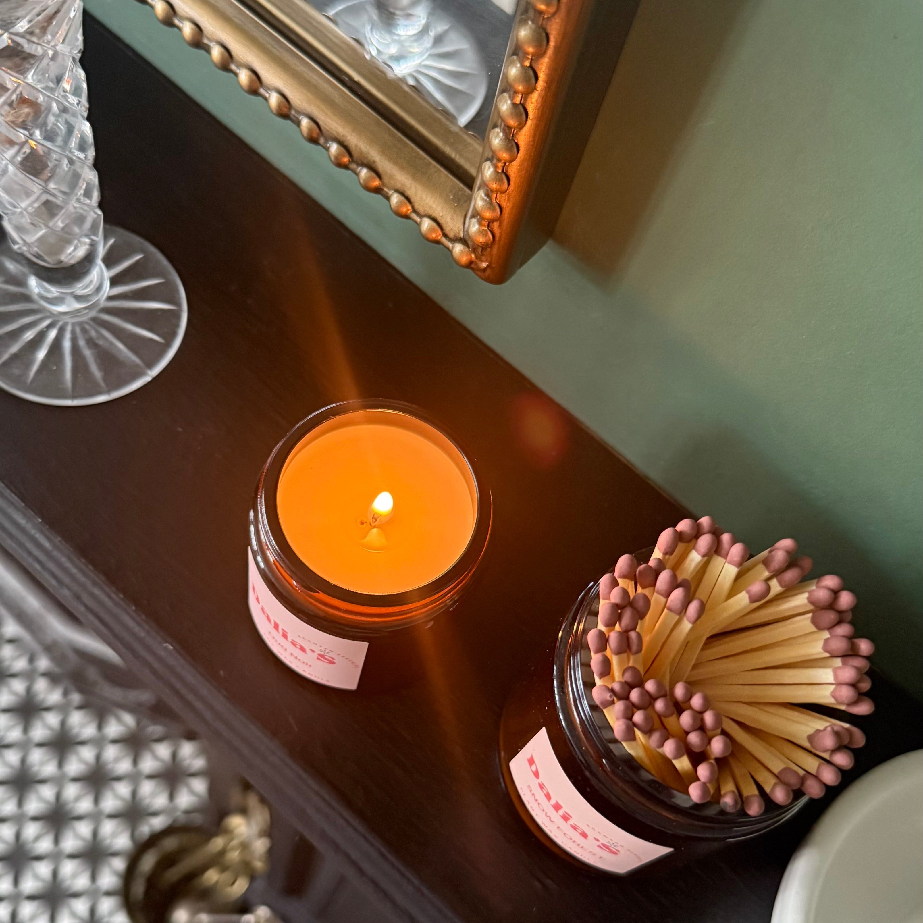 Candle and match holder on a wooden surface with decorative elements.