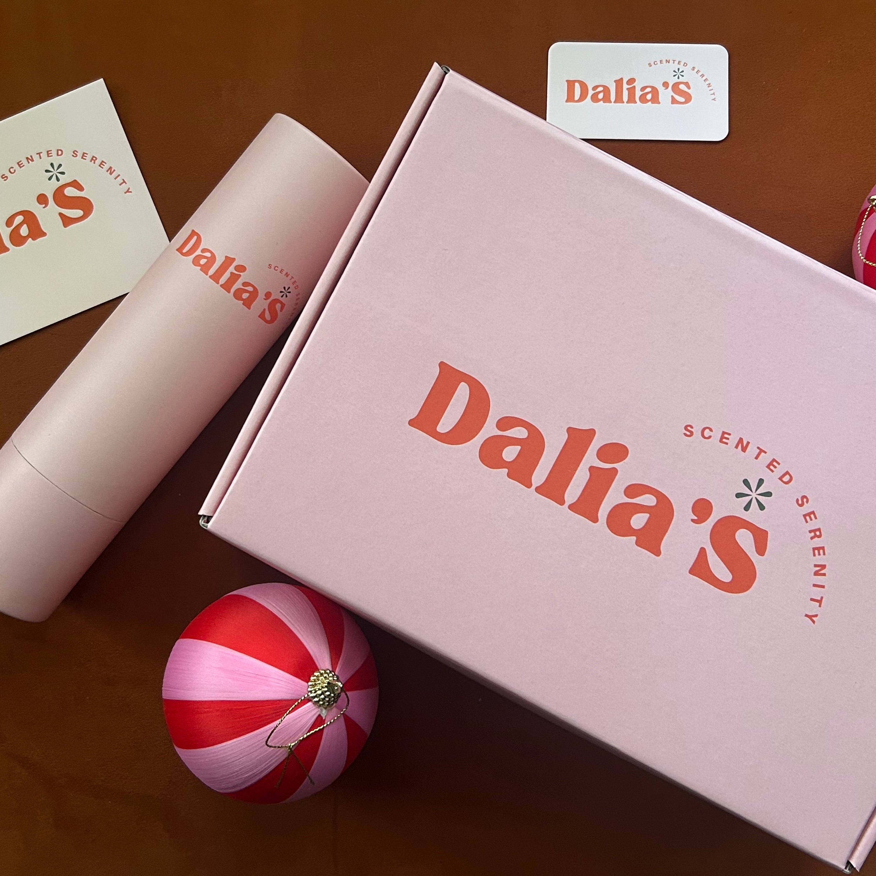 A gift set from Dalia's with a pink box labeled 'Refresh Gift Set', containing a candle and a reed diffuser with 'Dalia's' branding on the packaging.